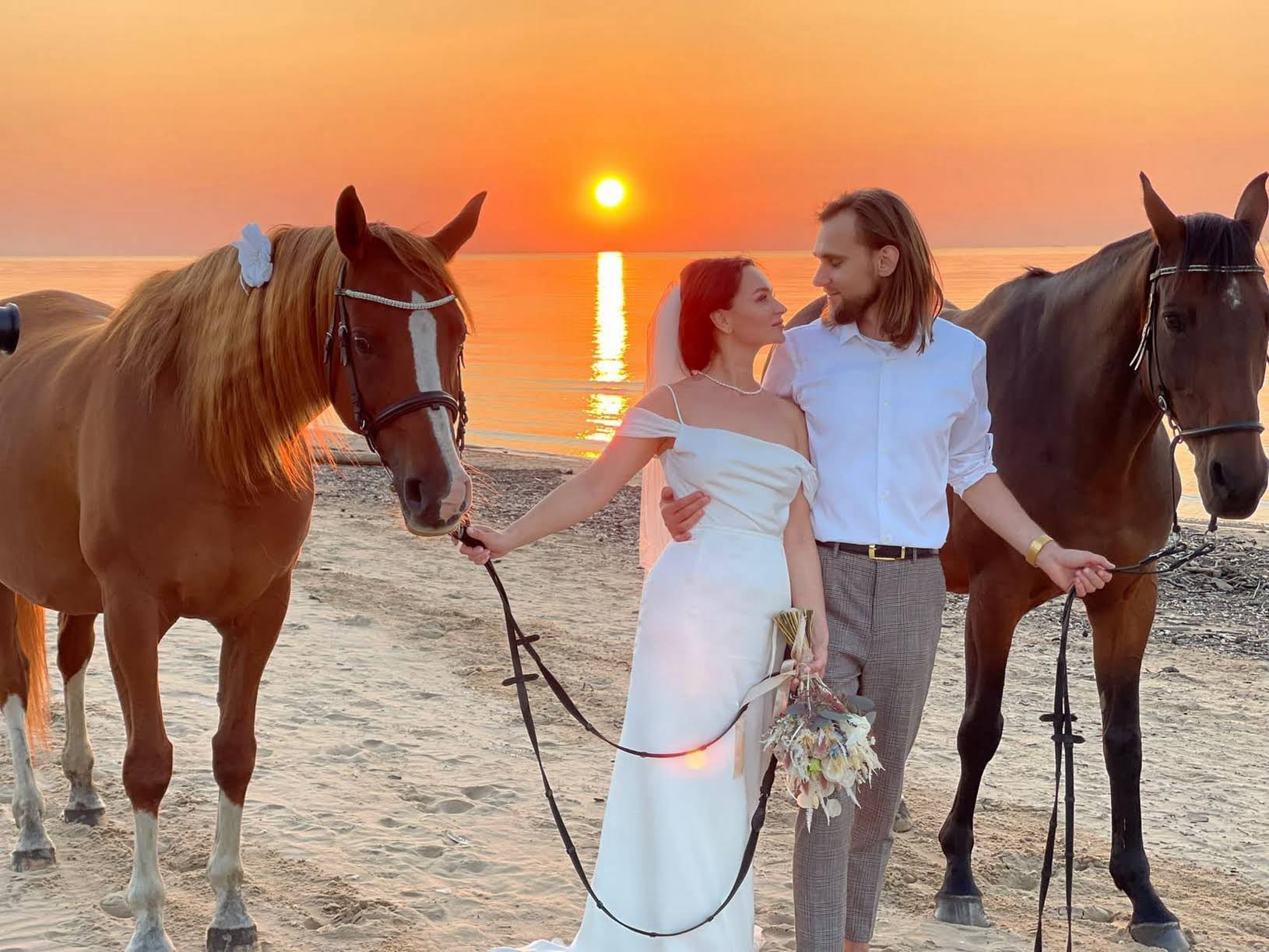 Kāzas jūras krastā ar zirgiem saulrietā