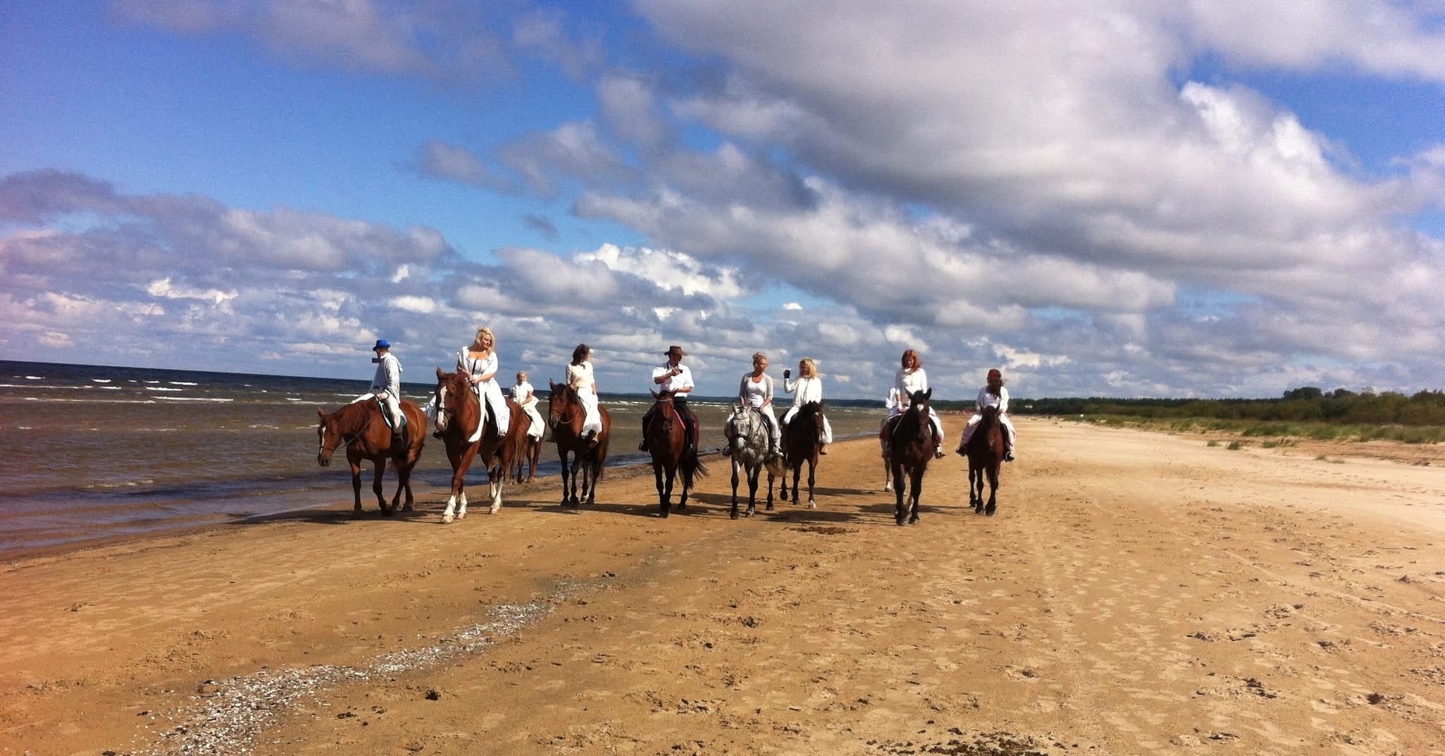 Svinēšana zirgu mugurās jūras krastā